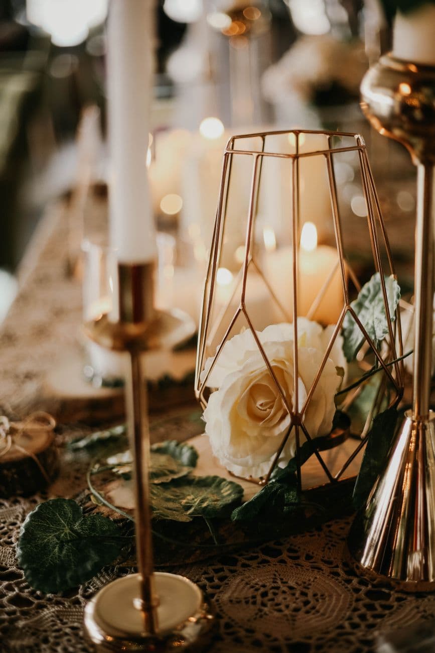 Elegant table setting with candles and white roses creating a romantic ambiance.